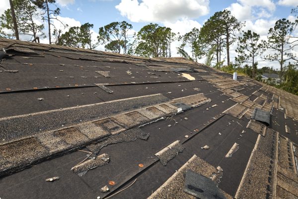 Damaged house roof with missing shingles after hurricane Ian in Florida. Consequences of natural disaster.